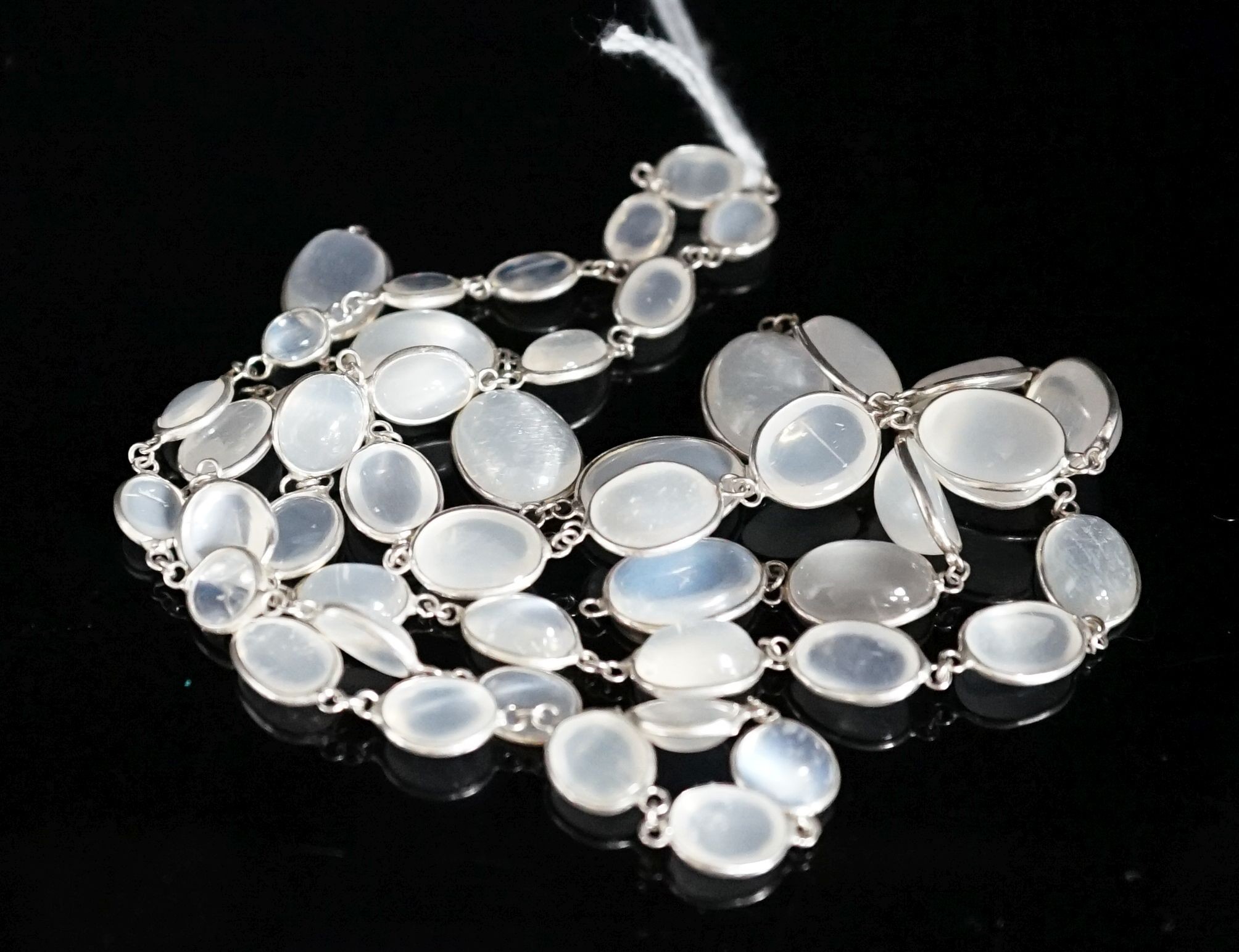 A modern (1980's) white metal and graduated moonstone set spectacle necklace, 69cm.